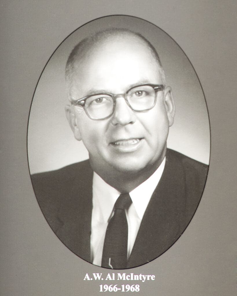 Black-and-white portrait of a man in a suit and glasses, framed by an oval border with a caption beneath (name and dates).