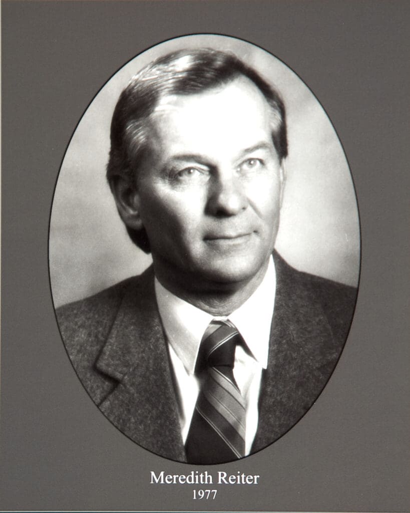 Yearbook portrait of Meredith Reiter, 1977, shown in a grayscale oval frame wearing a suit and striped tie.