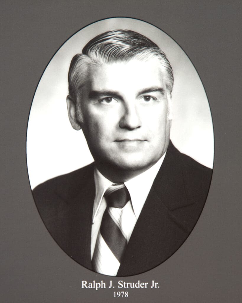 Black-and-white formal portrait of Ralph J. Struder Jr. in a suit and tie, framed in an oval on a gray background (1978).
