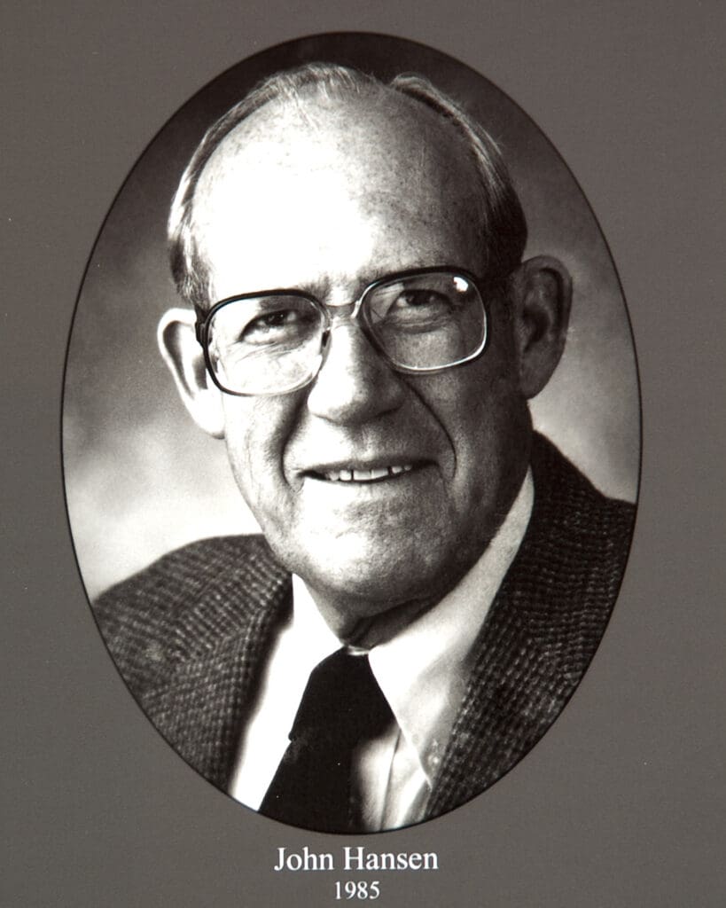 Oval black-and-white portrait of John Hansen in a suit and tie, 1985 photo.