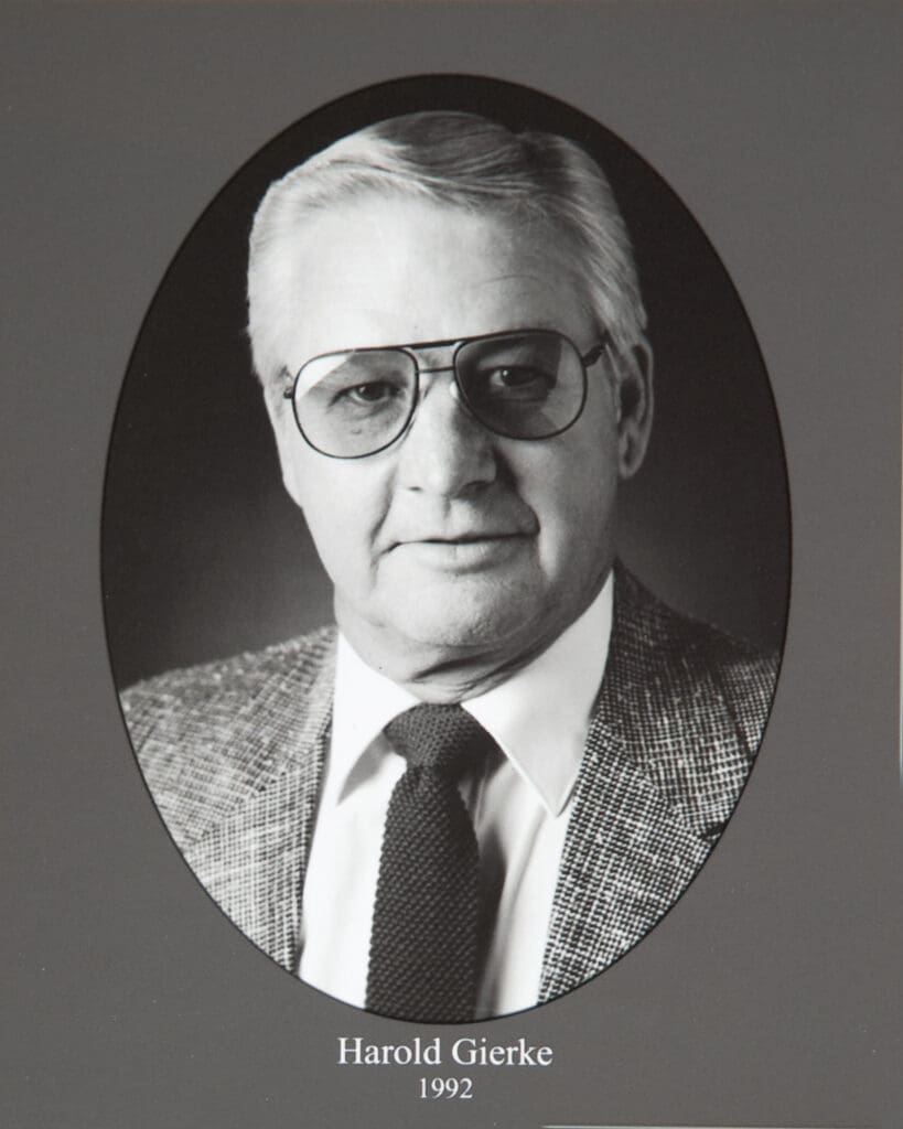 Oval black-and-white portrait of Harold Gierke wearing glasses and a checkered suit, with a tie; caption reads'Harold Gierke 1992'.