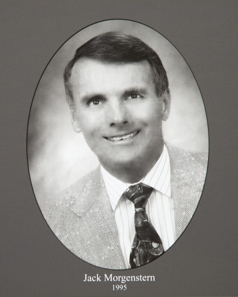 Oval black-and-white portrait of a smiling man in a suit and striped shirt, labeled Jack Morgenstern, 1995