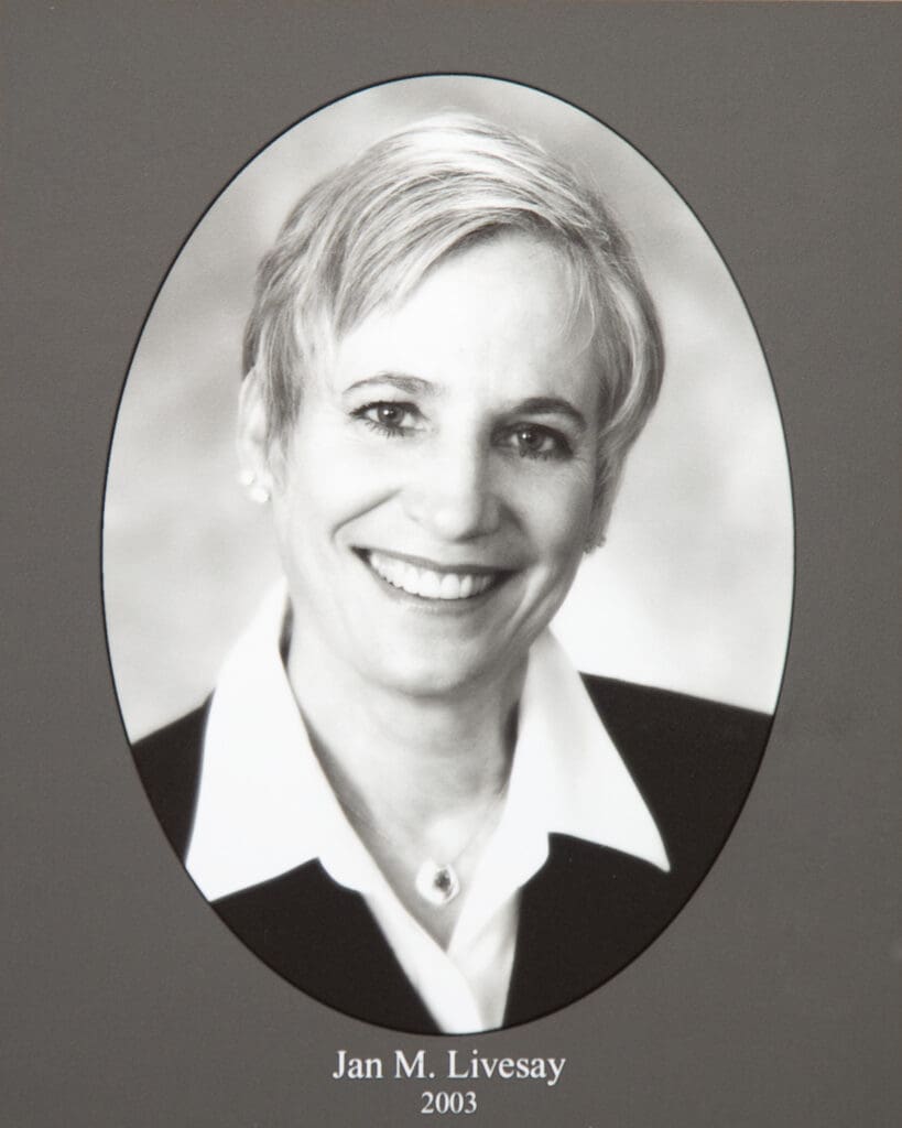 Smiling woman in a white blouse inside an oval photo frame against a dark background; caption reads Jan M. Livesay, 2003 (black-and-white portrait).