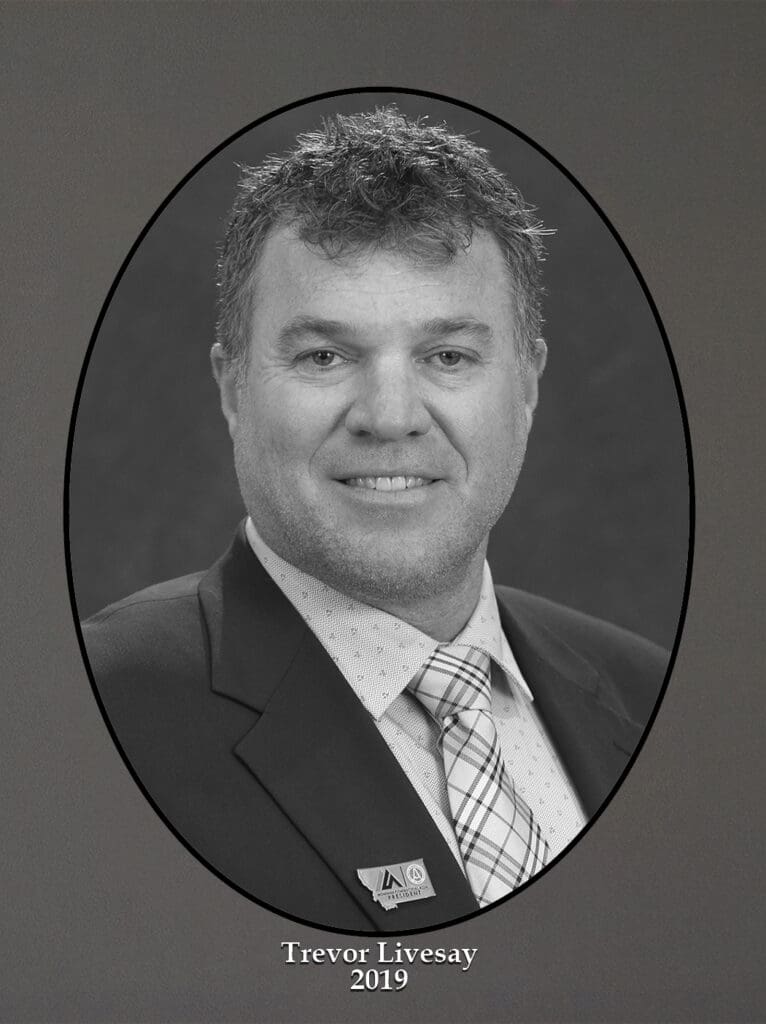 Formal black-and-white portrait of Trevor Livesay in a suit and patterned tie, oval frame, 2019 date printed below
