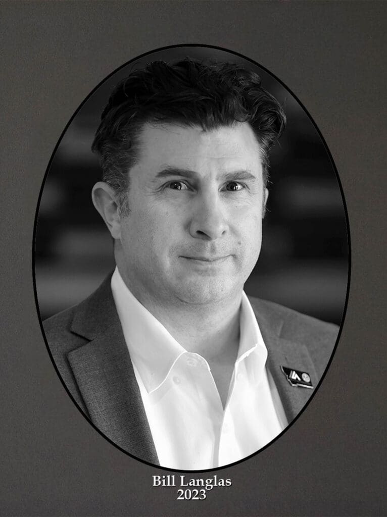 Black-and-white portrait of a man in a suit inside an oval frame, labeled 'Bill Langlas, 2023'.